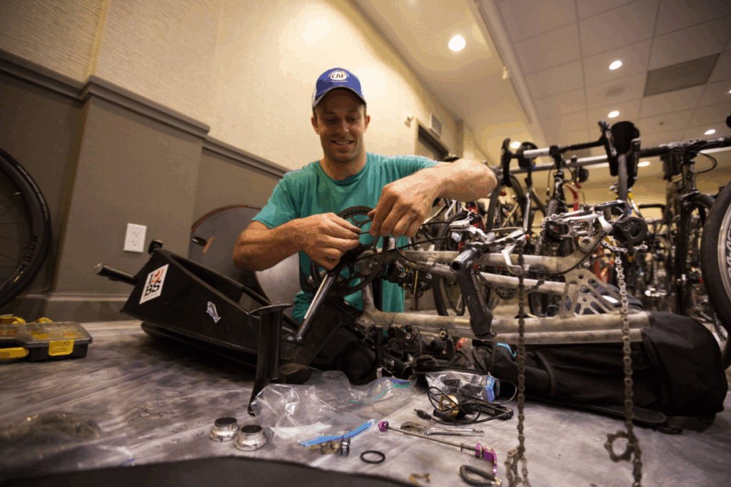 Andre Kajlich working on repairing his handcycle indoors, surrounded by tools and spare parts.