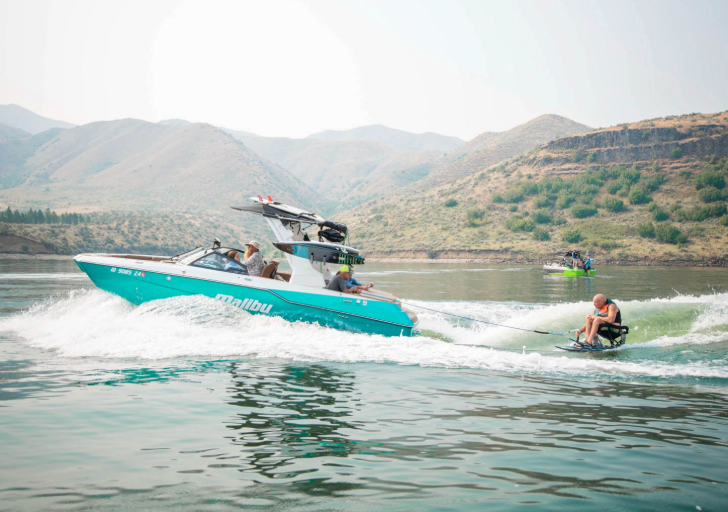 Motorboat on a lake with a person water-skiing, set against a backdrop of hills.