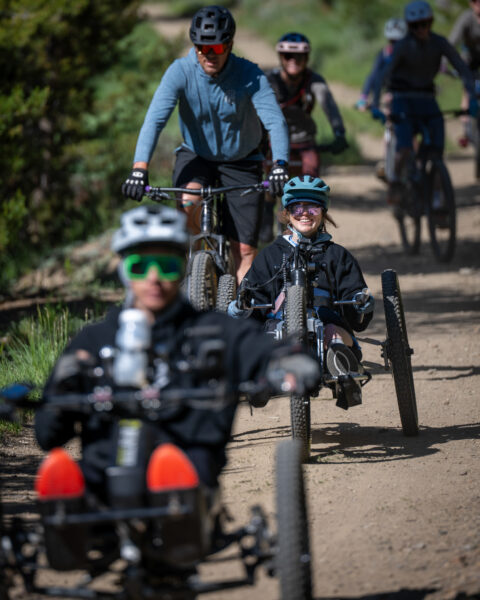 Group of cyclists on a dirt trail, including riders on recumbent handcycles.