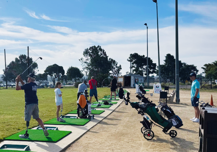 Athletes with physical disabilities line up on a driving range hitting golf balls during a CAF adaptive golf clinic in Southern California.